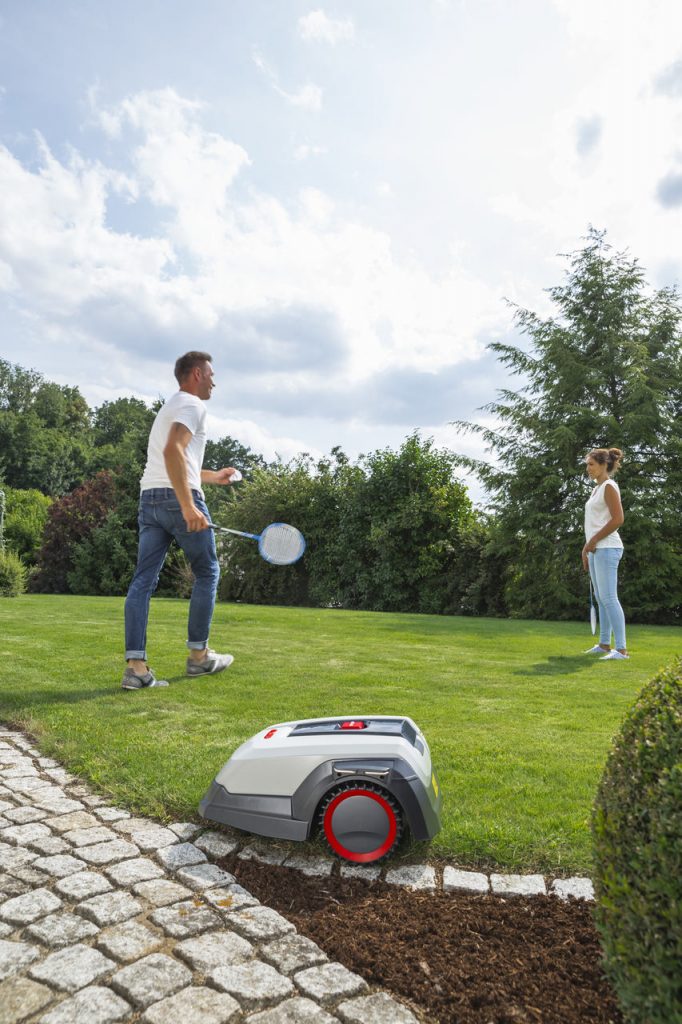 robot koszący na tle pary grającej w badmintona